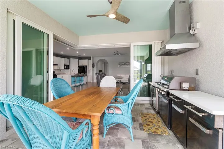 Outdoor kitchen with stainless steel appliances, white countertops, and a stainless steel range hood. 16160 Bluestem Ln. Babcock Ranch, FL 33982