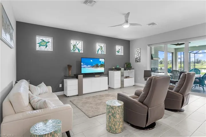 Large format floor tile, ceiling fan, sliding glass doors, white cabinetry, dark accent wall. 16160 Bluestem Ln. Babcock Ranch, FL 33982