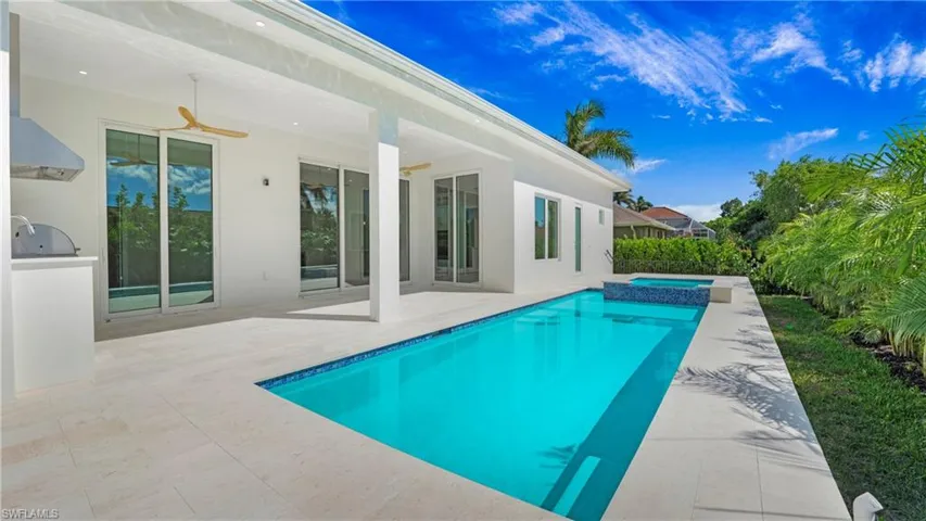 View of pool featuring ceiling fan, a patio, a pool with connected hot tub, and area for grilling