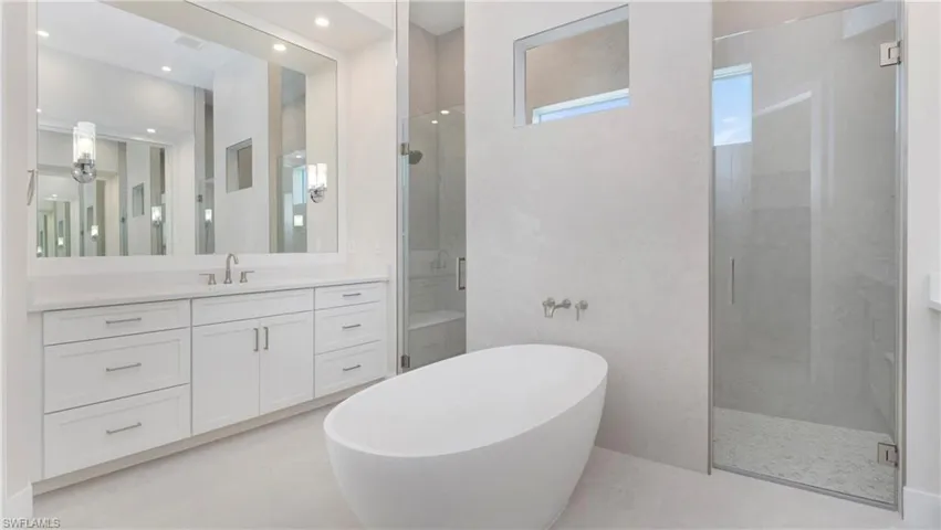 Bathroom featuring a stall shower, vanity, and a soaking tub