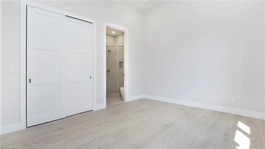 Unfurnished bedroom with light wood finished floors, a closet, ensuite bathroom, and recessed lighting