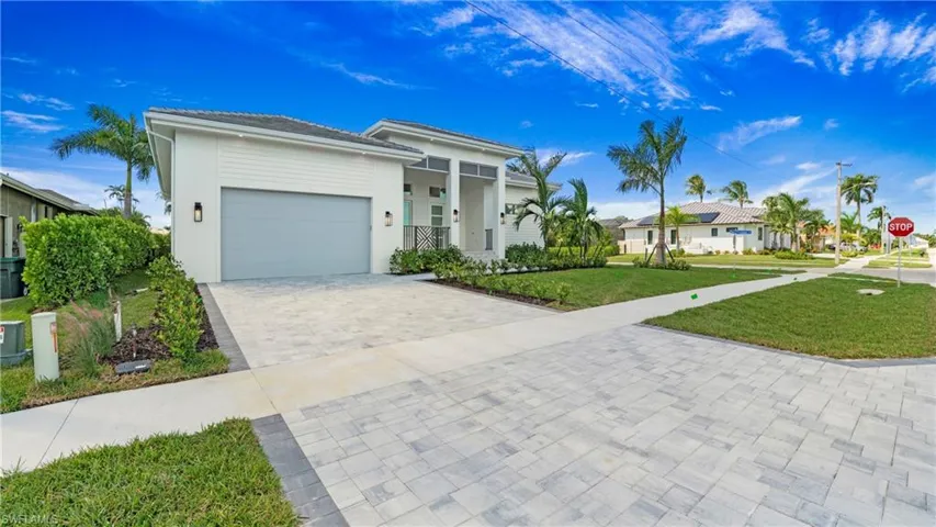View of front of property featuring a front yard, an attached garage, covered porch, decorative driveway, and stucco siding