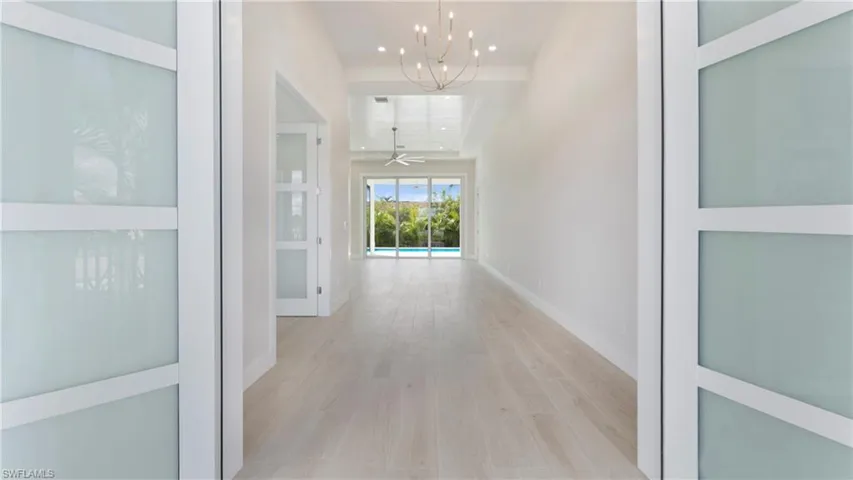 Hall with light wood-style floors, a chandelier, and recessed lighting