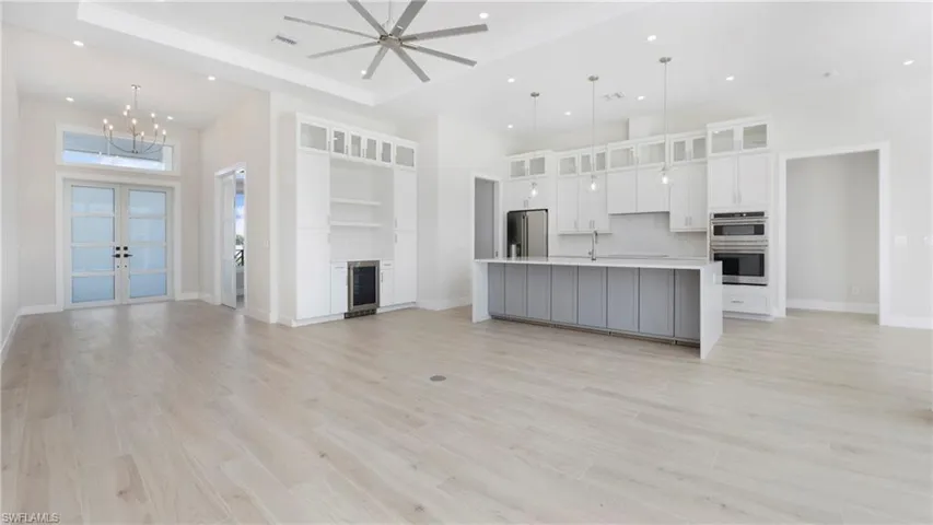 Unfurnished living room featuring french doors, a high ceiling, light wood-type flooring, recessed lighting, and ceiling fan