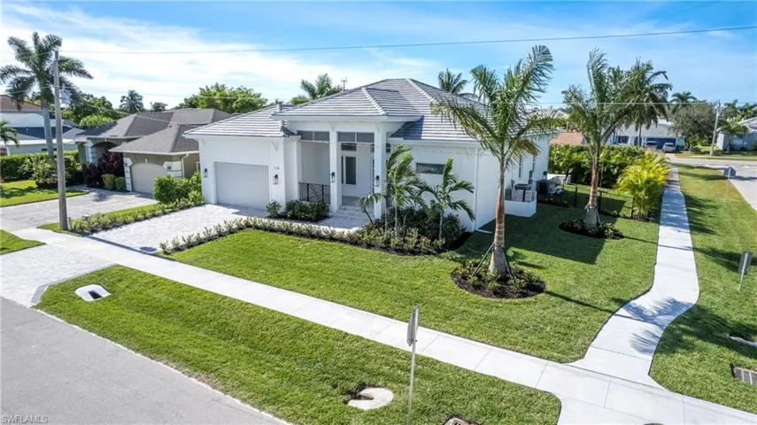 View of front facade featuring decorative driveway, a front yard, and stucco siding