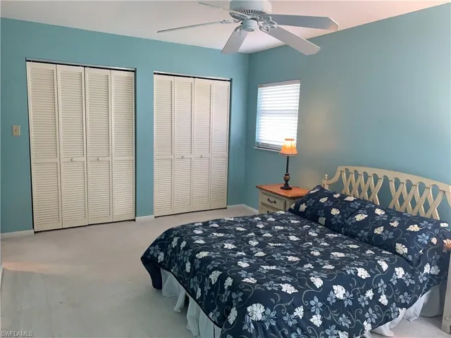 Carpeted bedroom featuring multiple closets and a ceiling fan