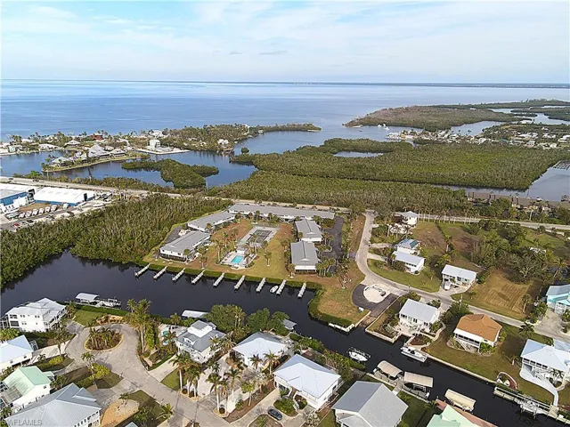 Aerial view of property and surrounding area featuring a nearby body of water and nearby suburban area