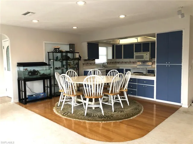 Dining area with wood finished floors, arched walkways, and recessed lighting