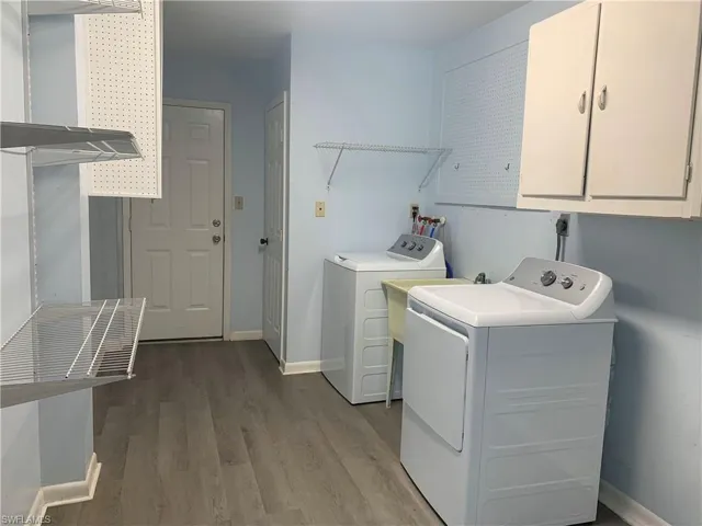 Laundry area featuring washer and dryer, wood finished floors, and cabinet space