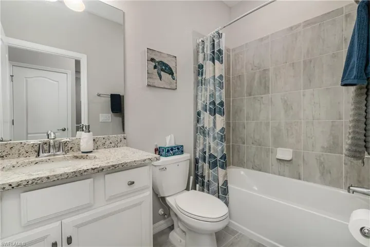 Full bath with toilet, vanity, and shower / bath combination with curtain
