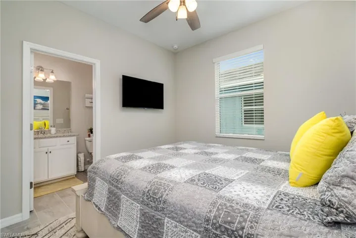 Bedroom featuring a ceiling fan, light tile patterned flooring, and ensuite bathroom