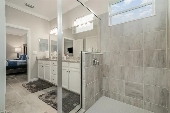Ensuite bathroom featuring ensuite bathroom, visible vents, crown molding, vanity, and a walk in shower