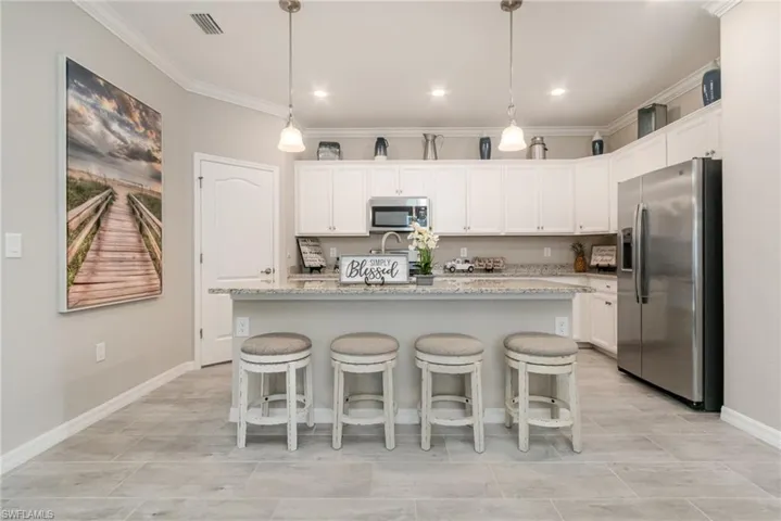 Kitchen featuring crown molding, an island with sink, white cabinets, and stainless steel appliances