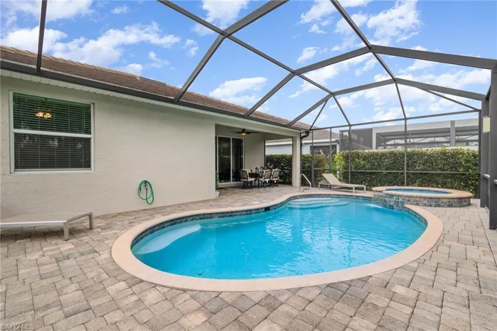 View of swimming pool with a pool with connected hot tub, a lanai, ceiling fan, and a patio area