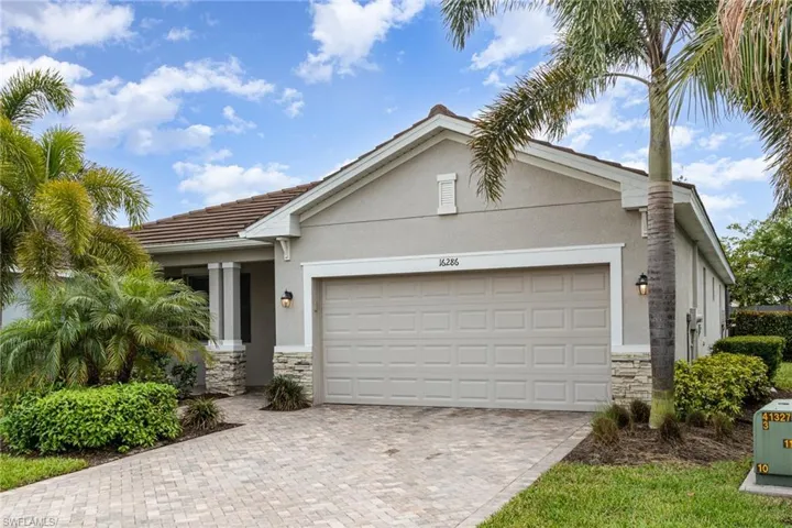 View of front of property featuring a tile roof, stucco siding, stone siding, and a garage