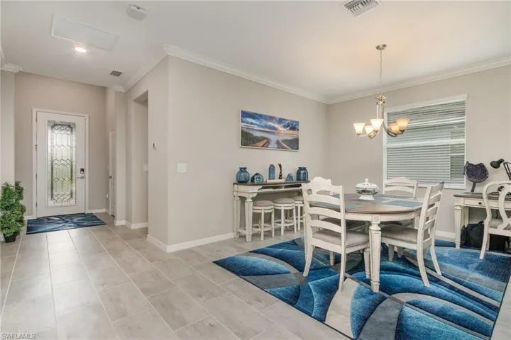 Dining room with baseboards, ornamental molding, visible vents, and a chandelier