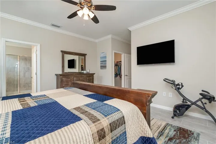Bedroom with crown molding, a ceiling fan, a spacious closet, baseboards, and visible vents