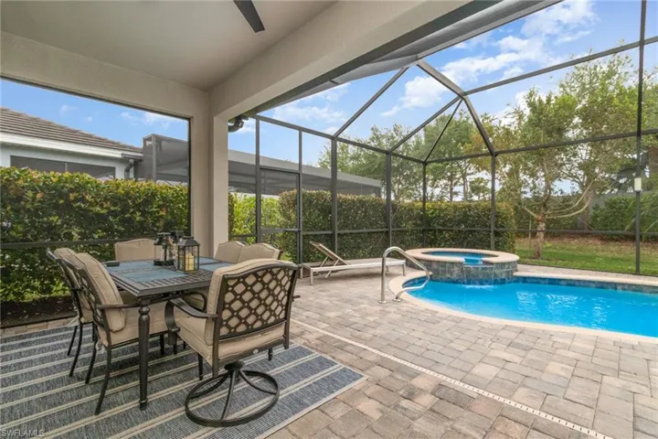View of pool with a pool with connected hot tub, glass enclosure, and a patio area