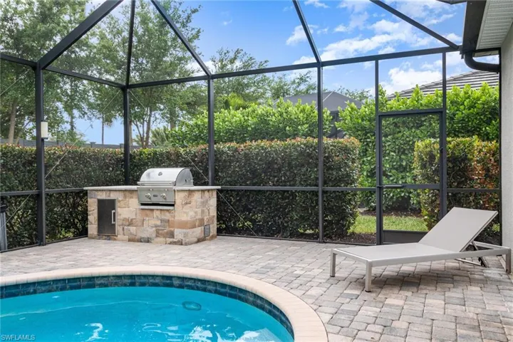 View of pool featuring a patio, exterior kitchen, grilling area, and a lanai