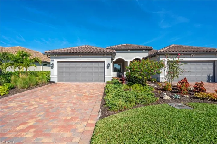 Mediterranean / Spanish-style attached villa featuring a garage, decorative driveway, stucco siding, and a tile roof