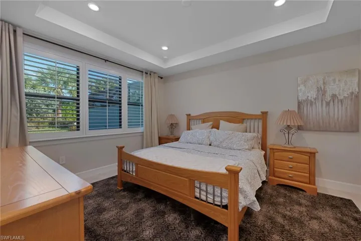 Bedroom featuring recessed lighting, a raised ceiling, and dark carpet