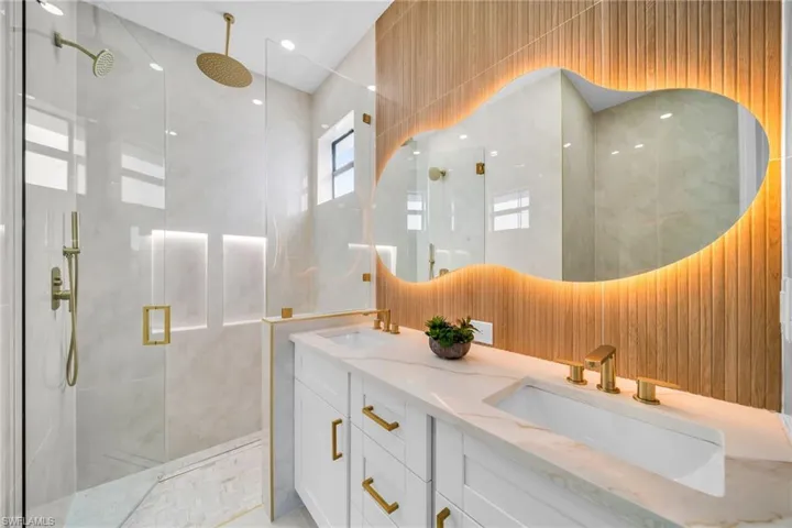Full bath with double vanity, a shower stall, tile walls, and recessed lighting