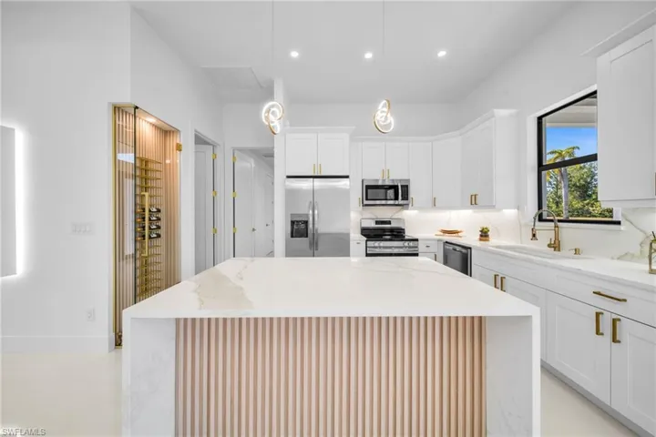 Kitchen with light stone counters, stainless steel appliances, and white cabinets
