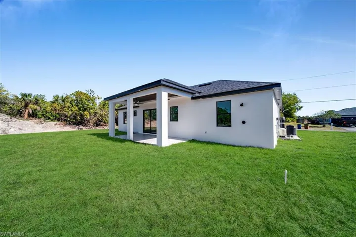 Rear view of property with a patio area, stucco siding, a yard, and a ceiling fan
