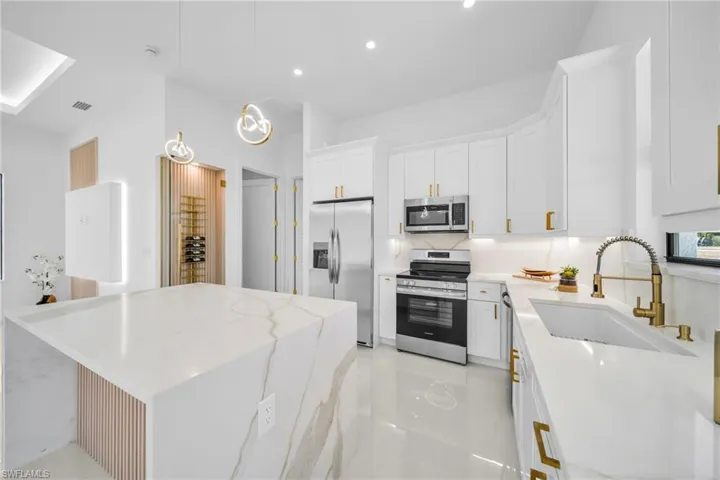 Kitchen with light stone countertops, stainless steel appliances, hanging light fixtures, and a center island