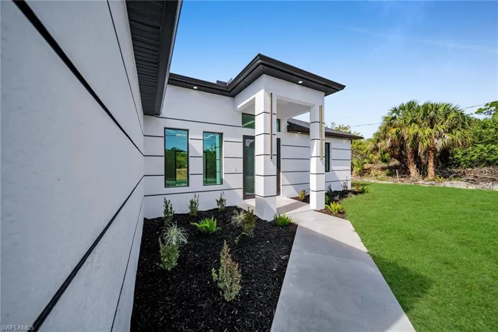 Property entrance featuring a lawn and stucco siding