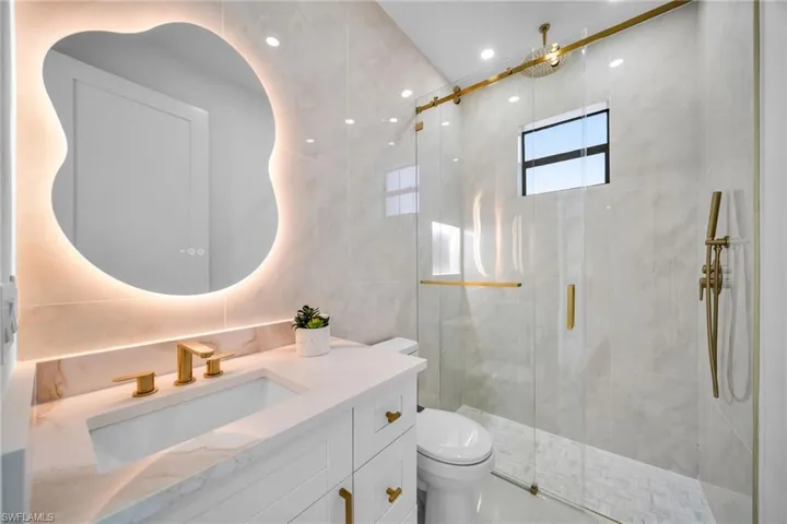 Full bathroom featuring a marble finish shower, vanity, tile walls, and recessed lighting