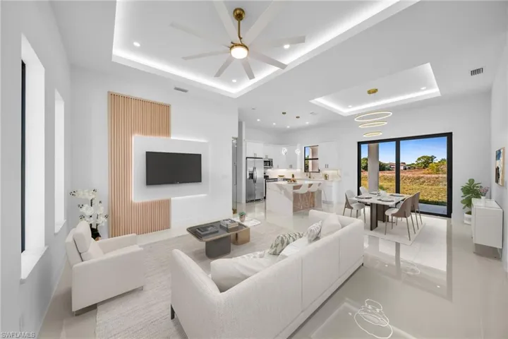 Living room with a raised ceiling, ceiling fan, and recessed lighting