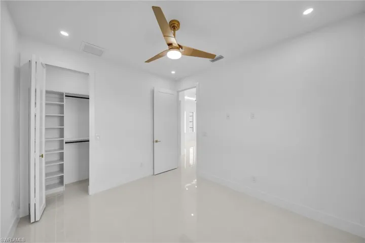 Unfurnished bedroom featuring a walk in closet, recessed lighting, ceiling fan, and light tile patterned floors