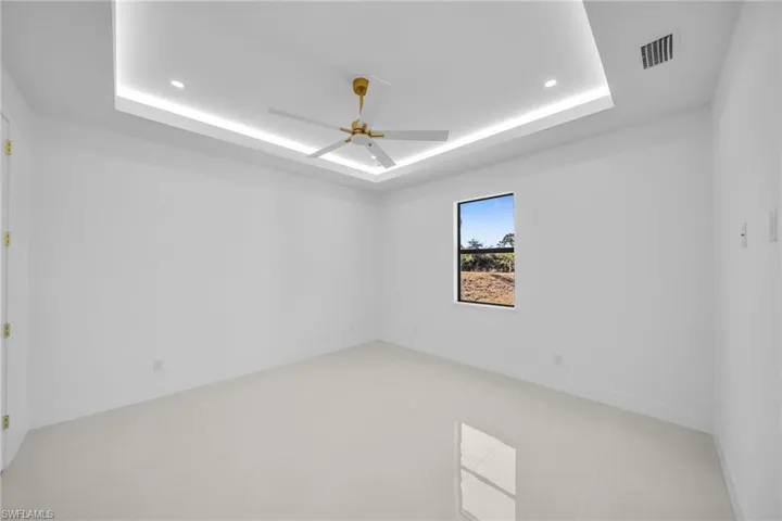 Spare room with a ceiling fan, a raised ceiling, and recessed lighting