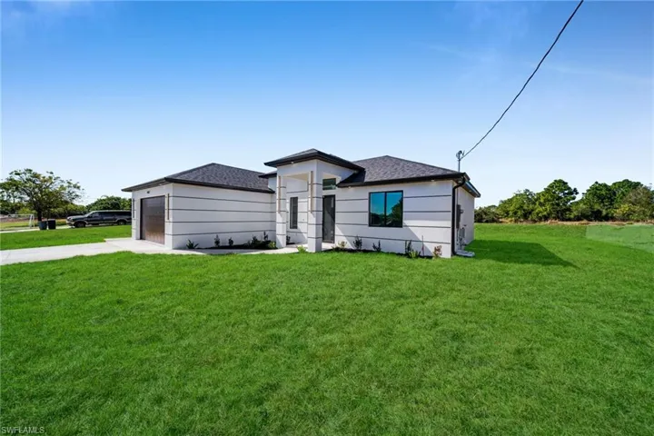 View of front facade with a front yard, driveway, a garage, and roof with shingles
