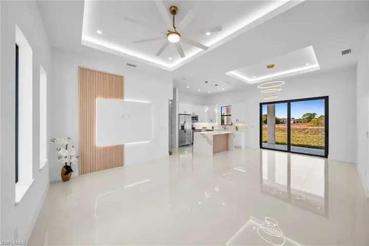 Unfurnished living room featuring a raised ceiling, recessed lighting, and ceiling fan