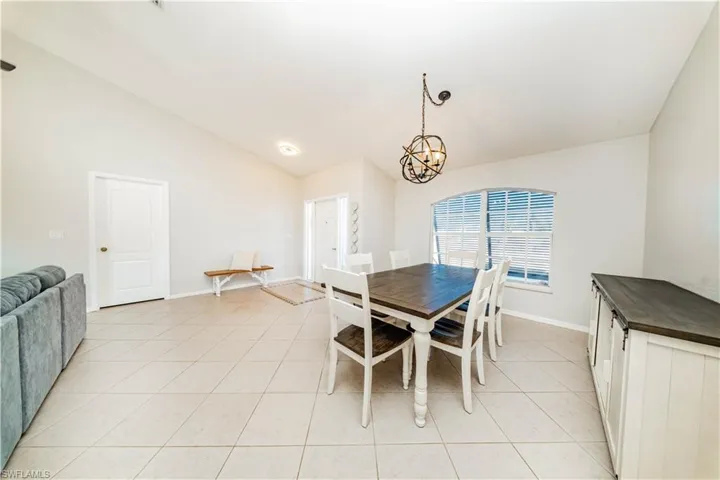 Dining space featuring vaulted ceiling, light tile patterned floors, and a chandelier