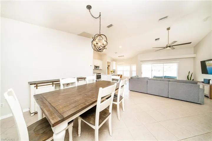 Dining area with lofted ceiling, a ceiling fan, light tile patterned floors, and hanging lights
