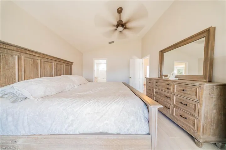 Bedroom with vaulted ceiling, ceiling fan, and ensuite bath