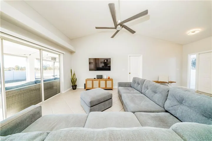 Living room featuring lofted ceiling, healthy amount of natural light, ceiling fan, and light tile patterned floors