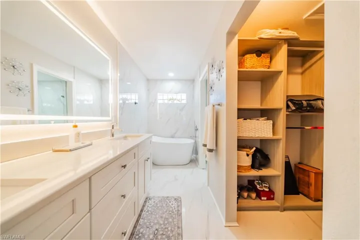 Full bath featuring a soaking tub, a marble finish shower, double vanity, light marble finish floors, and recessed lighting