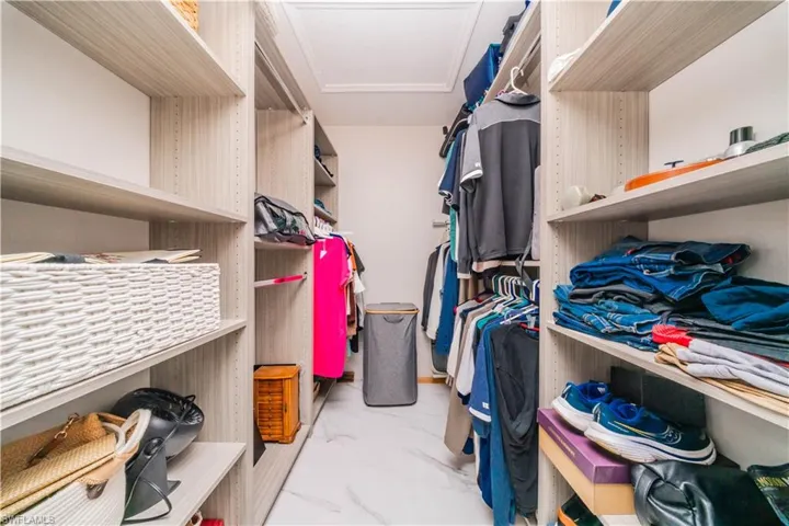Walk in closet with light marble finish floors and attic access