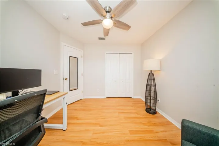 Office area with light wood-style flooring and ceiling fan