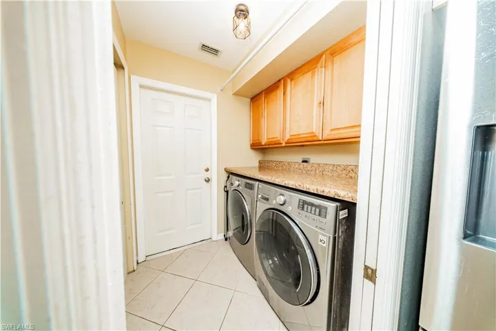 Laundry room featuring light tile patterned floors, independent washer and dryer, and cabinet space