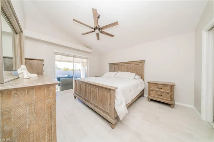 Bedroom with access to exterior, lofted ceiling, ceiling fan, and light wood-type flooring