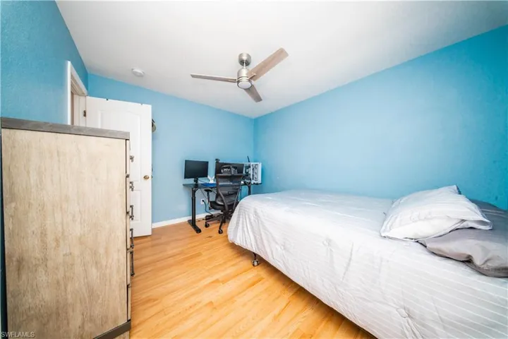 Bedroom featuring light wood-type flooring, a ceiling fan, and a desk