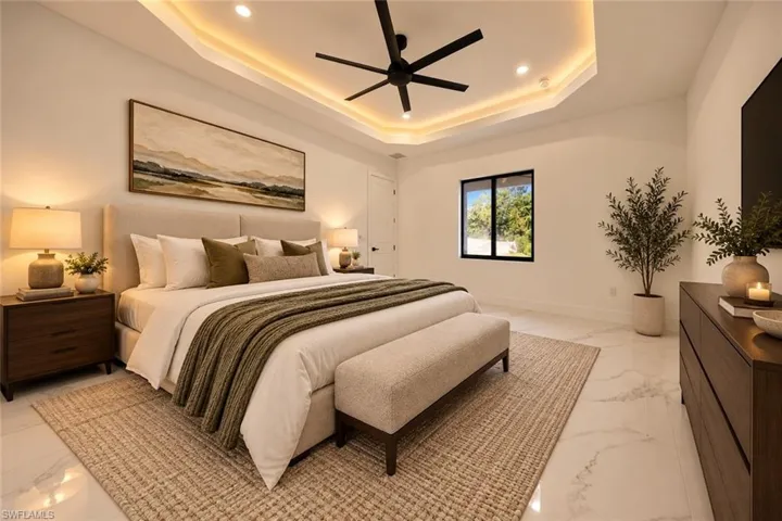 Tray ceiling with cove lighting and recessed lighting, ceiling fan, large window with dark trim, white tile flooring, and a solid wood dresser