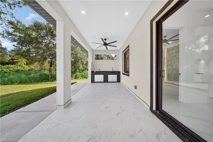 Covered patio featuring recessed lighting, ceiling fan, outdoor kitchen with built-in cabinetry, and sliding glass doors