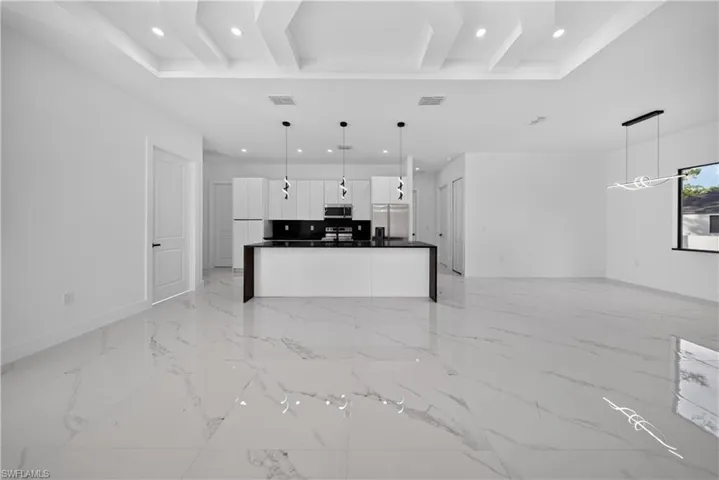 Open-concept living area with large-format white tile flooring, a tray ceiling, and recessed lighting