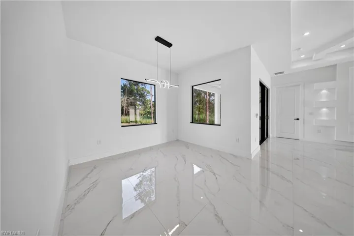 Spacious room with white walls, large format tile flooring, and a contemporary pendant light fixture